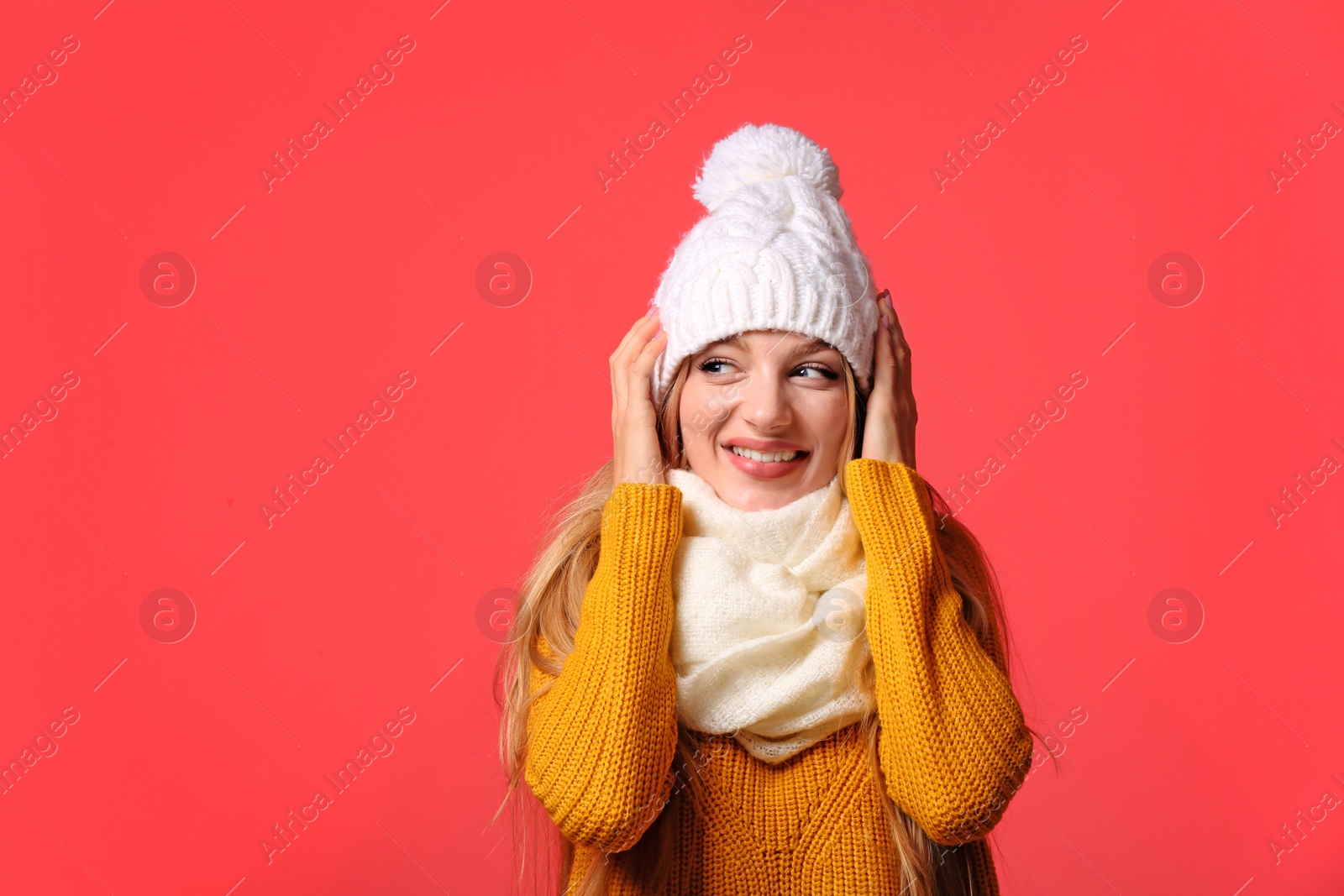 Photo of Portrait of emotional young woman in stylish hat, sweater and scarf on color background. Winter atmosphere
