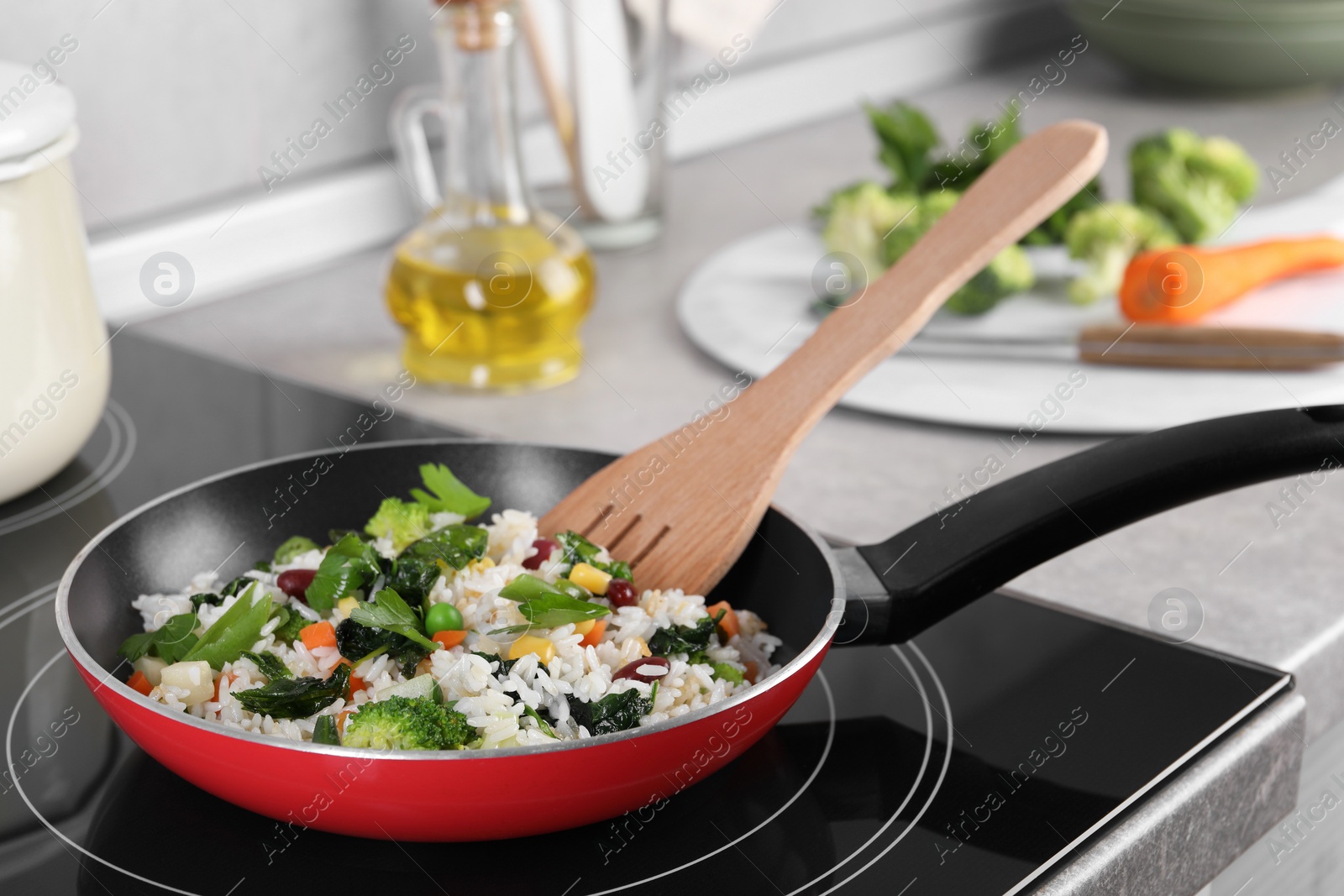 Photo of Frying tasty rice with vegetables on induction stove in kitchen, closeup