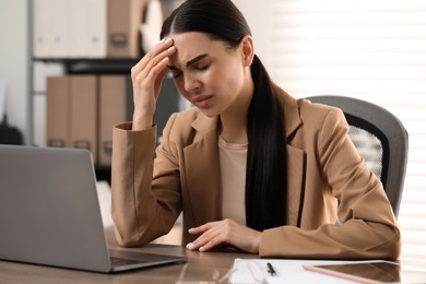 Woman suffering from headache at workplace in office