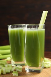 Glasses of delicious celery juice and vegetables on wooden board