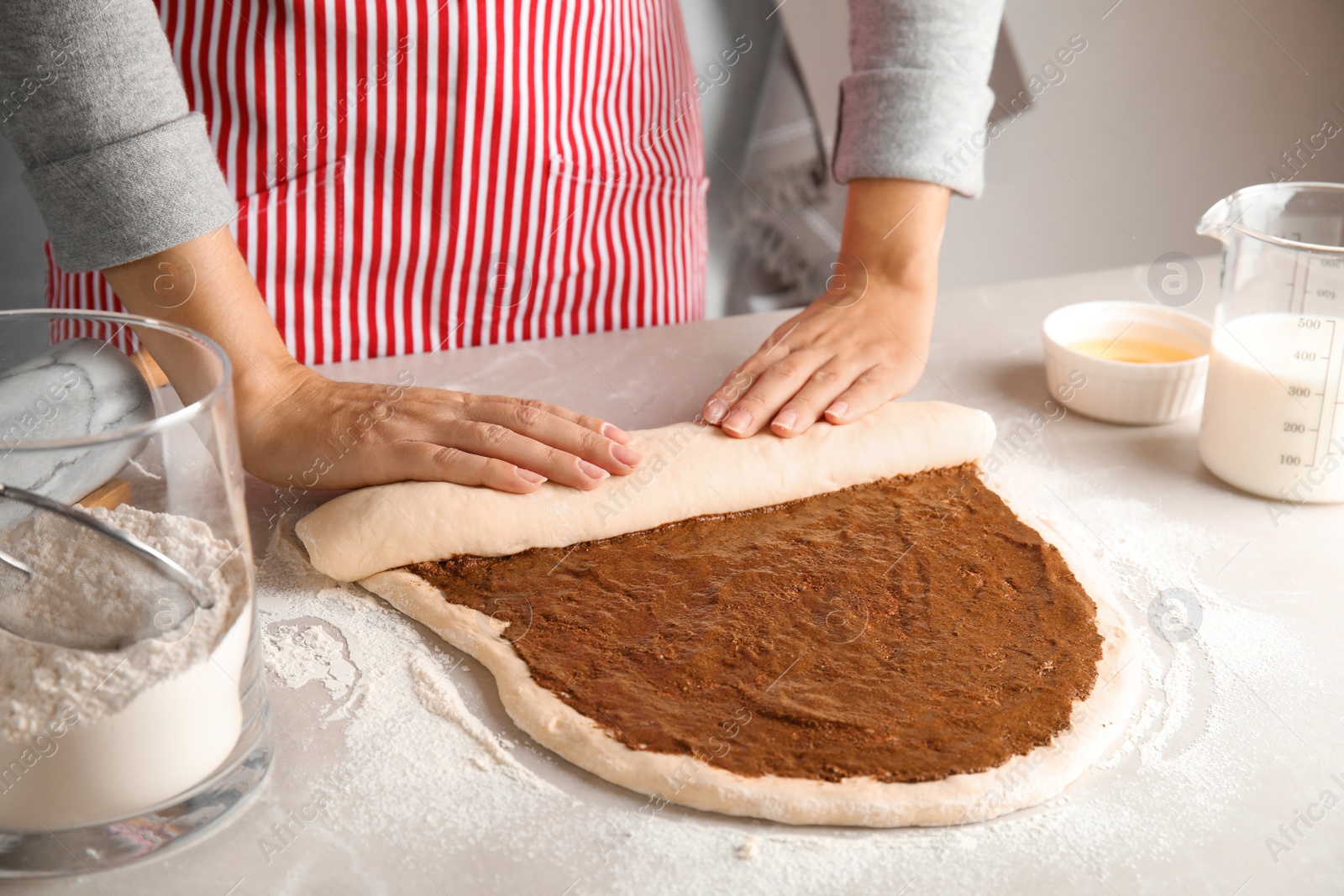 Photo of Woman making cinnamon rolls at table, closeup