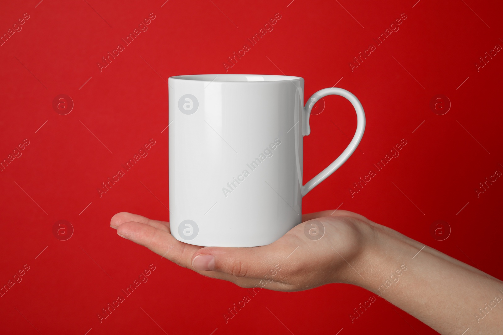 Photo of Woman holding white mug on red background, closeup