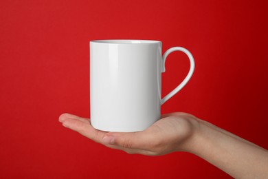 Photo of Woman holding white mug on red background, closeup