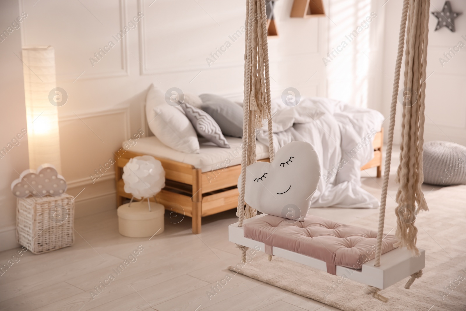 Photo of Beautiful swing with toy heart in bedroom. Stylish interior design