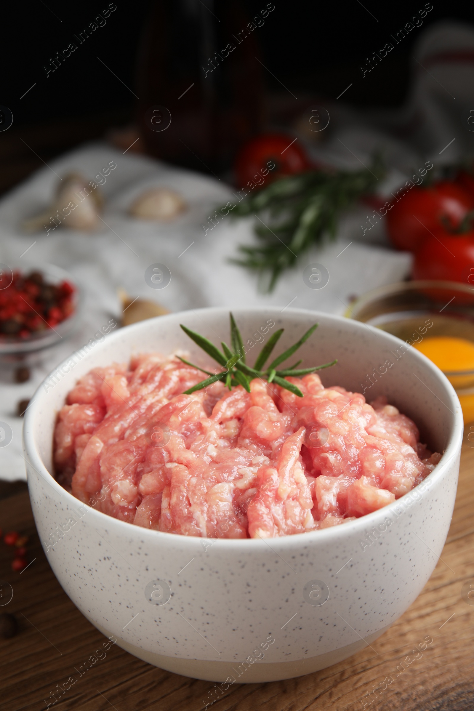 Photo of Raw chicken minced meat with rosemary on wooden table
