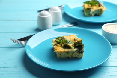 Photo of Tasty broccoli casserole served on blue wooden table