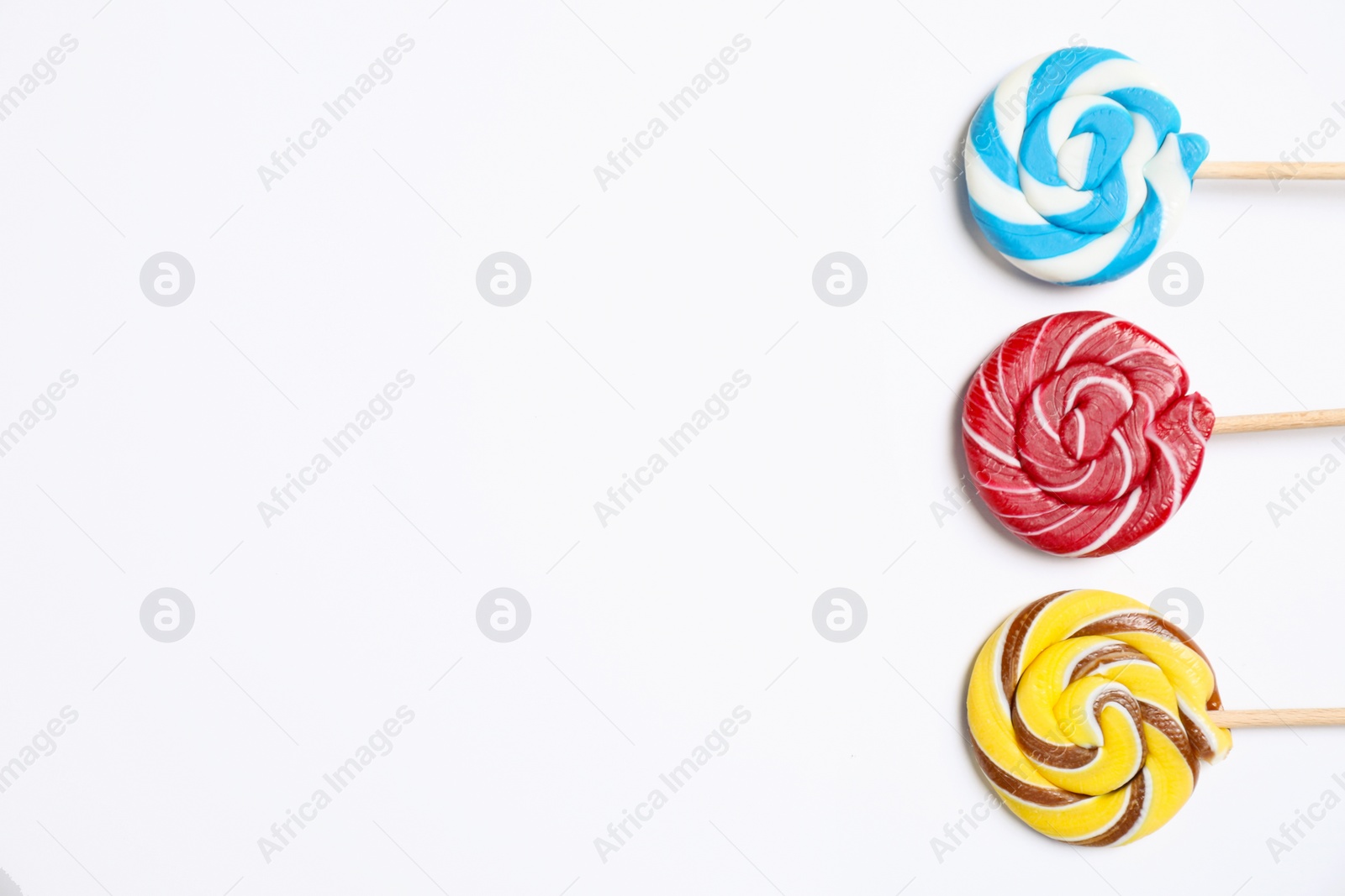 Photo of Sticks with colorful lollipops on white background, flat lay. Space for text