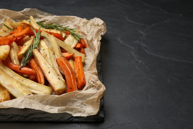 Photo of Parchment with tasty baked parsnip and bell pepper on dark grey table, space for text