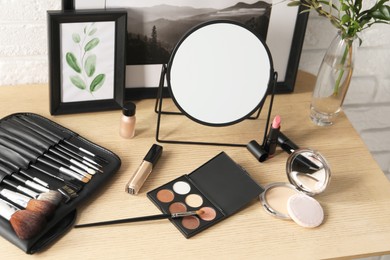 Photo of Mirror, makeup products and pictures on wooden dressing table