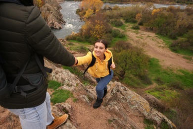 Couple of hikers with backpacks climbing up mountains