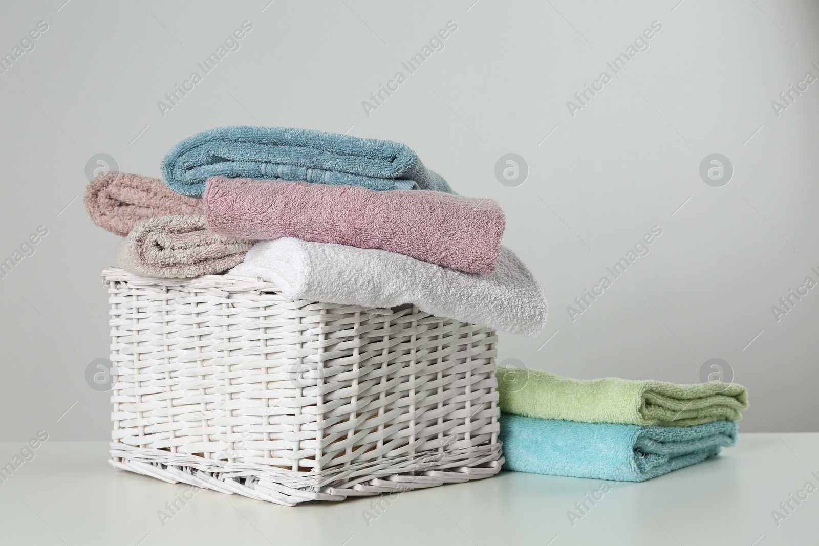 Photo of Wicker basket with clean soft towels on light background