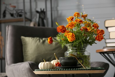 Beautiful autumn flowers, cup of drink and pumpkins on coffee table indoors