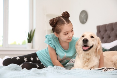 Photo of Cute little child with her pet on bed at home