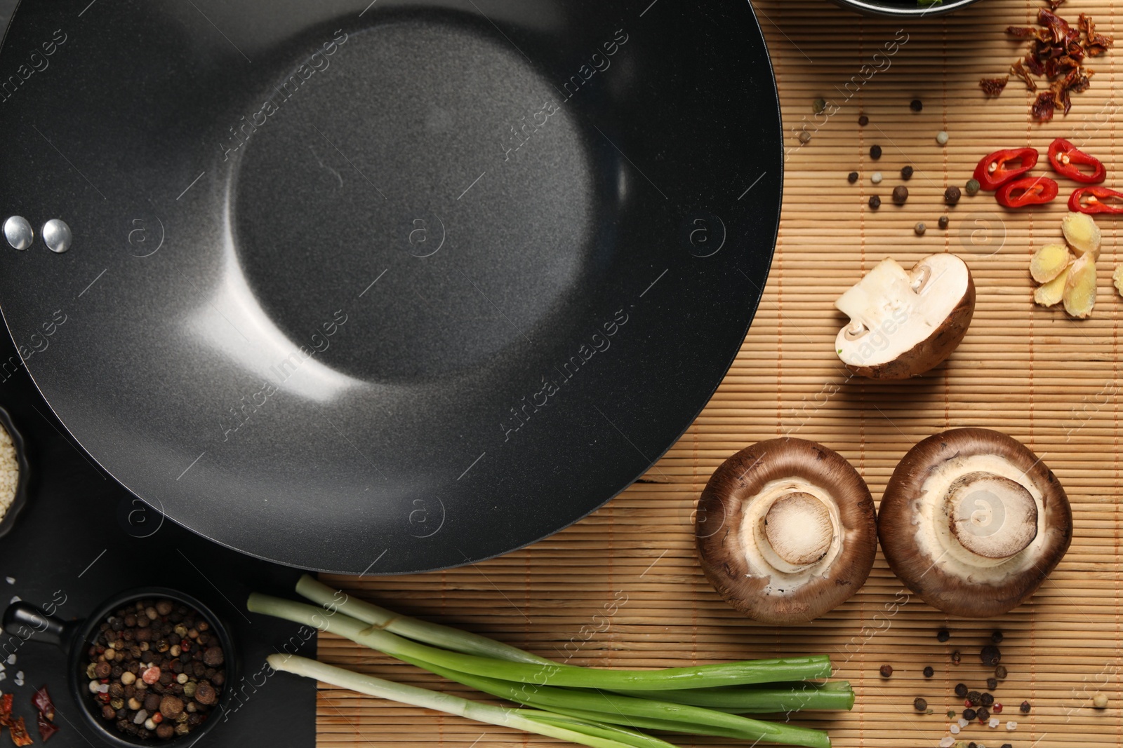 Photo of Flat lay composition with black wok, spices and products on dark table