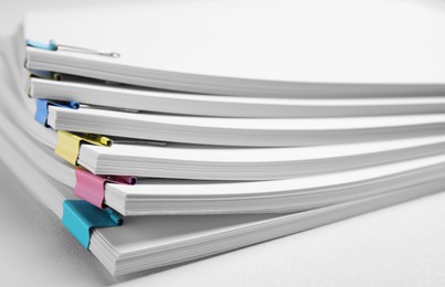 Photo of Many sheets of paper with colorful clips on white background, closeup