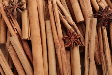 Photo of Aromatic cinnamon sticks and anise as background, top view