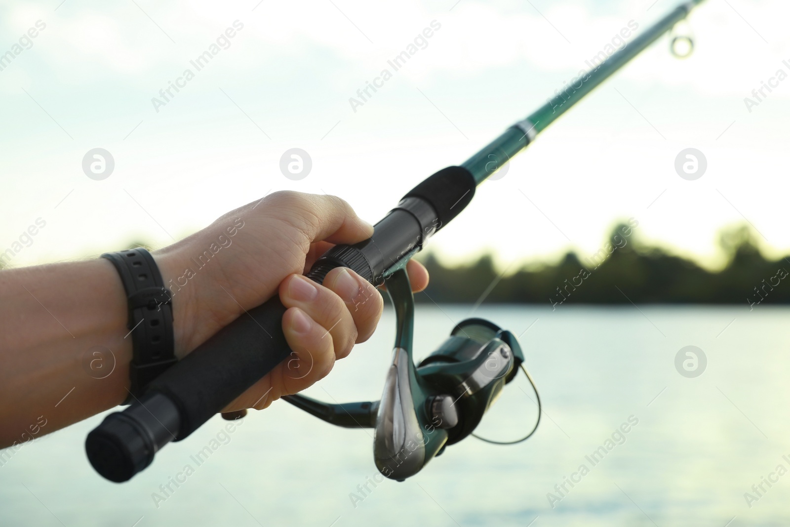 Photo of Fisherman with rod fishing at riverside, closeup