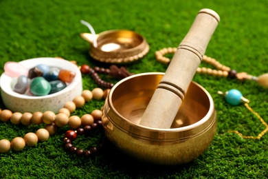 Photo of Composition with golden singing bowl on green grass, closeup. Sound healing