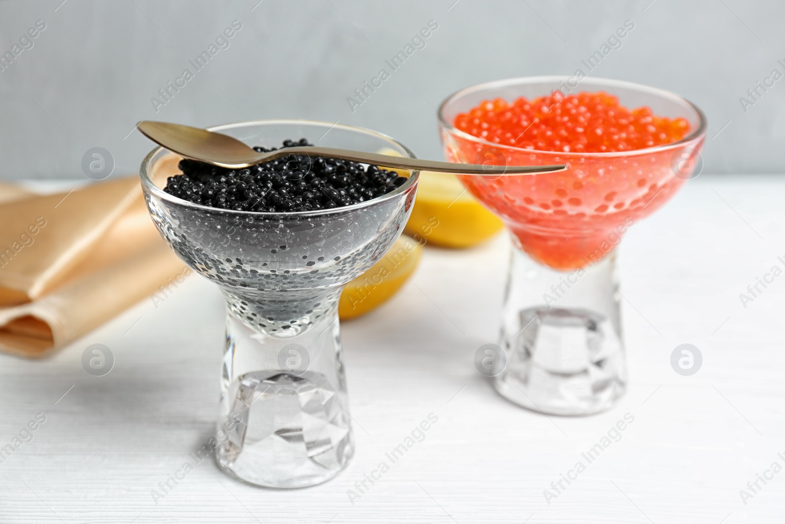 Photo of Glass bowls with black and red caviar on table