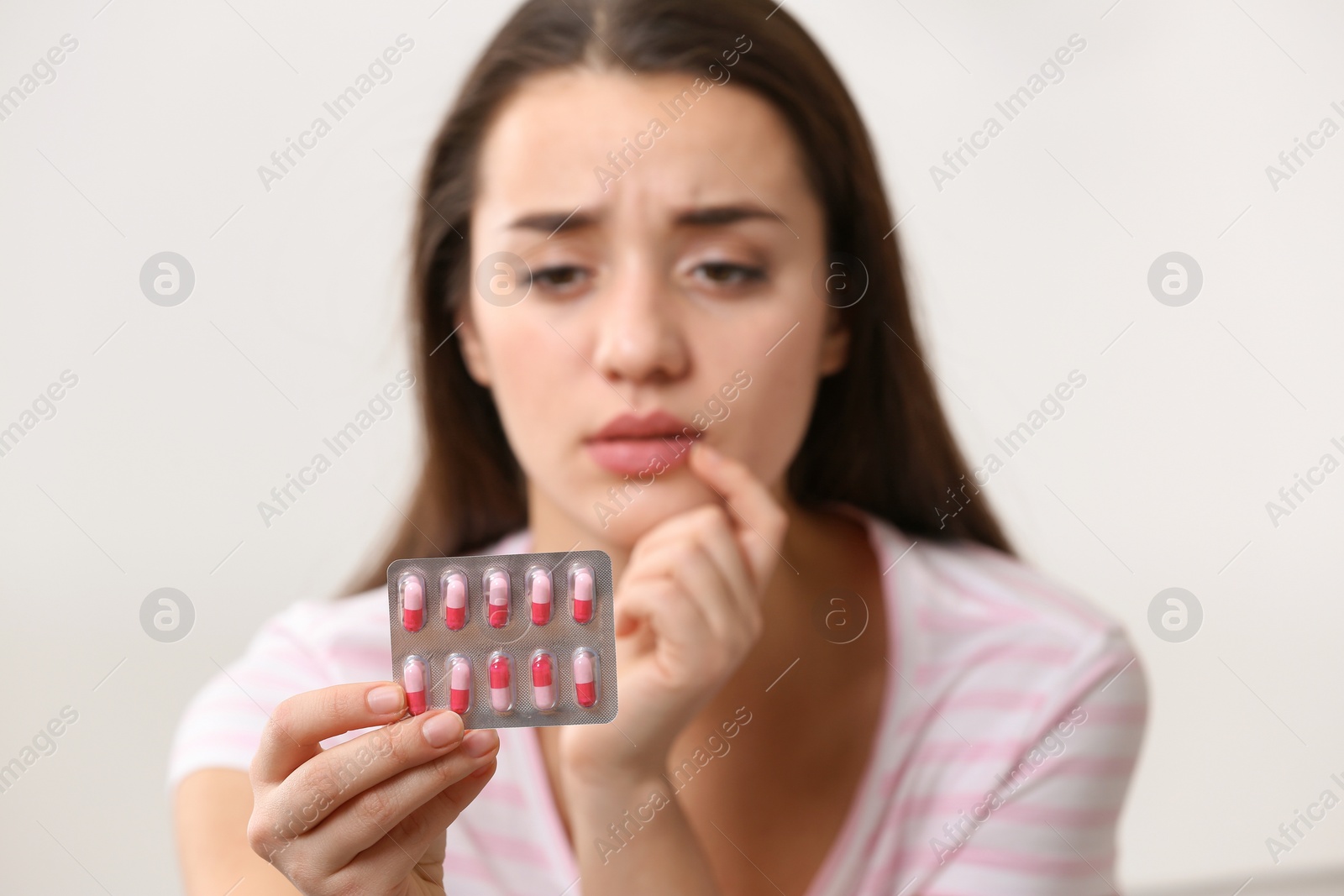 Photo of Young woman with pills on light background, closeup