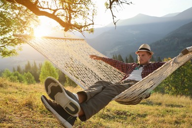 Photo of Man resting in hammock outdoors at sunset