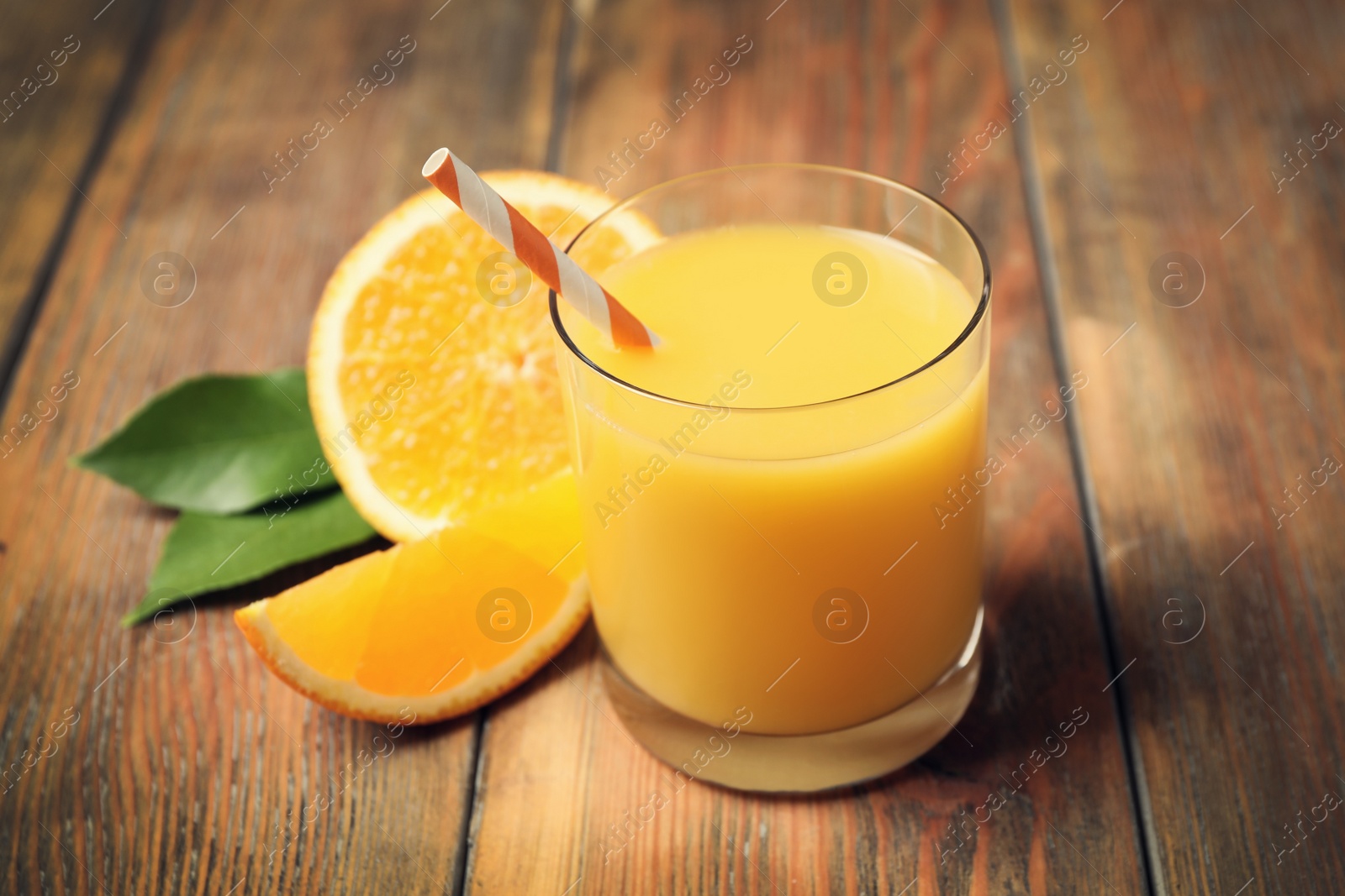 Photo of Glass of orange juice and fresh fruits on wooden table, closeup