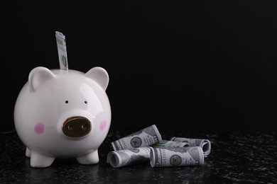 Photo of Financial savings. Piggy bank and dollar banknotes on black textured table