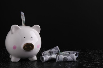 Financial savings. Piggy bank and dollar banknotes on black textured table