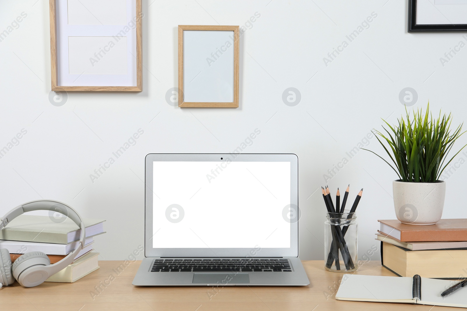 Photo of Cozy workspace with laptop and stationery on wooden desk at home