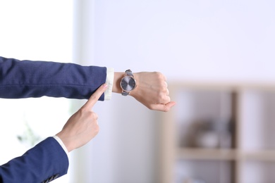 Businesswoman with wristwatch on blurred background. Time concept