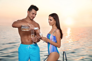 Photo of Young man and his girlfriend in bikini drinking champagne on yacht