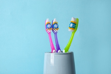 Photo of Cup with toothbrushes against color background