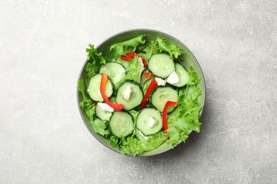 Photo of Delicious salad with cucumbers, red bell pepper and feta cheese in bowl on light grey table, top view