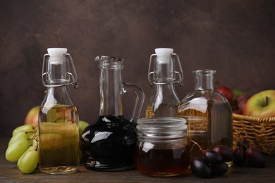 Different types of vinegar and fresh fruits on wooden table