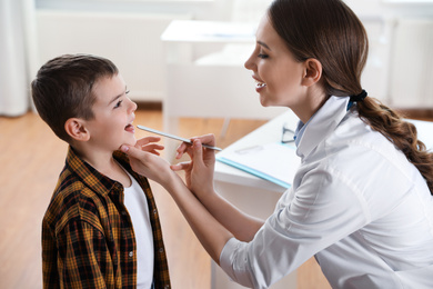 Photo of Children's doctor examining little patient's throat in clinic