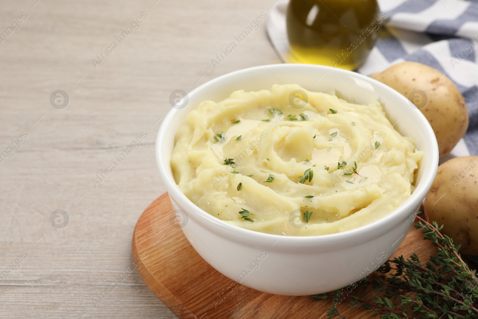 Photo of Bowl of tasty mashed potato with rosemary on beige wooden table, space for text