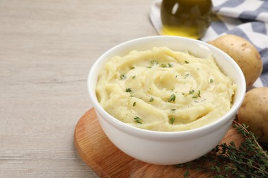 Bowl of tasty mashed potato with rosemary on beige wooden table, space for text
