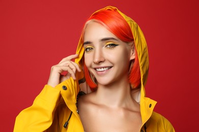 Beautiful young woman with bright dyed hair on red background