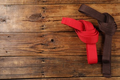 Photo of Red and brown karate belts on wooden background, flat lay