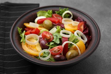 Photo of Bowl of tasty salad with leek and olives on brown table, closeup