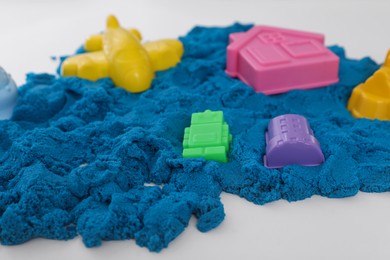 Bright kinetic sand and toys on white table