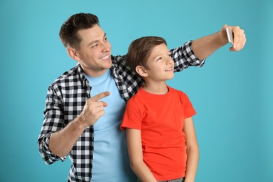 Photo of Dad and his son taking selfie on color background