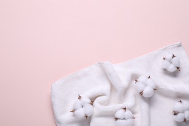 Photo of Fluffy cotton flowers and white terry towel on beige background, top view. Space for text