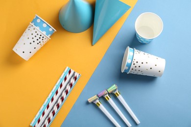 Party hats and other bright decor on color background, flat lay