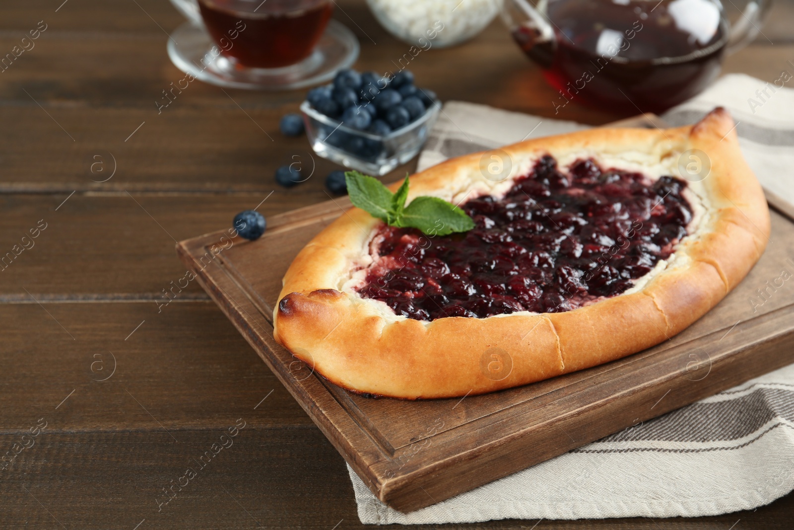 Photo of Delicious sweet cottage cheese pastry with cherry jam on wooden table. Space for text