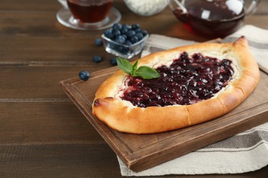Photo of Delicious sweet cottage cheese pastry with cherry jam on wooden table. Space for text