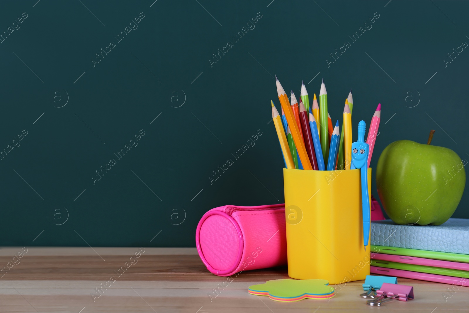 Photo of Composition with stationery and apple on table near chalkboard, space for text. Doing homework