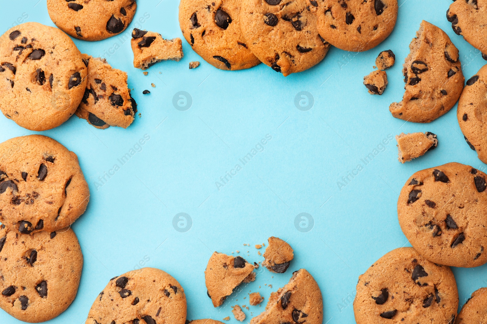 Photo of Frame made of many delicious chocolate chip cookies on light blue background, flat lay. Space for text