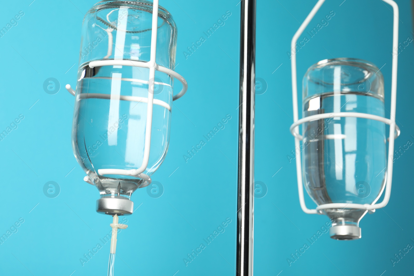 Photo of IV infusion set on pole against light blue background, closeup