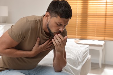Photo of Man suffering from pain during breathing on bed at home